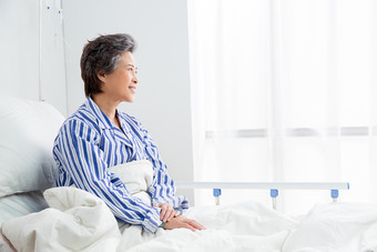 老年患者坐在医院病床上户内照片