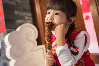 小女孩坐在门口吃糖葫芦