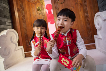 可爱的男孩女孩坐在门口吃糖葫芦四合院照片