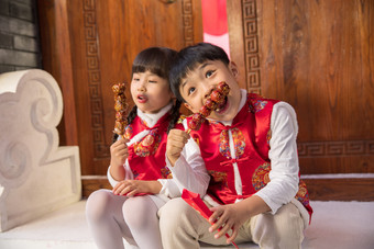 可爱的男孩女孩坐在门口吃糖葫芦中式庭院素材