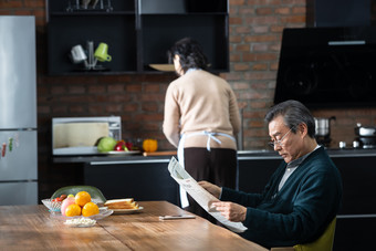 老年人看报纸做饭家庭生活健康生活方式摄影图