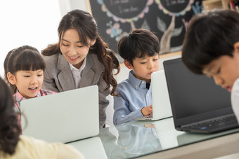 老师辅导学生使用电脑青年女人户内勤奋