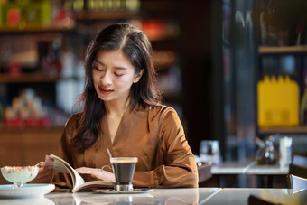 青年女人在咖啡厅里看书人照片