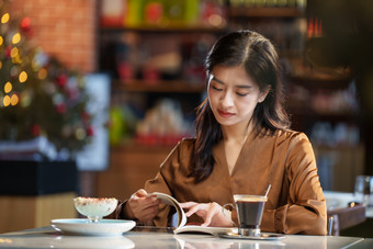 青年女人在咖啡厅里看书人摄影