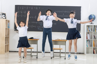 快乐<strong>的</strong>小学生在教室里欢呼跳跃友谊摄影图