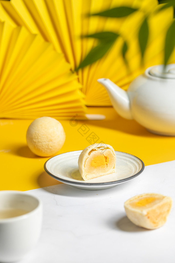 黄白色背景前的椰蓉酥和白色茶壶图片