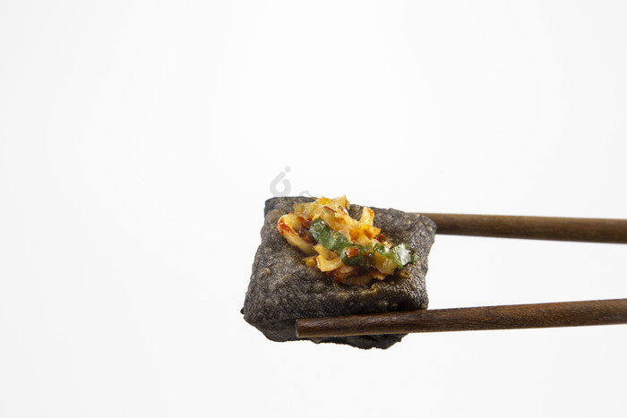 用筷子夹着的臭豆腐特写图片