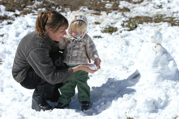 母子俩在雪地里玩，<strong>堆雪人</strong>