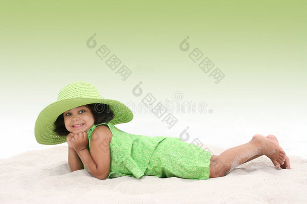 戴着绿色大帽子躺在沙滩上的漂亮女孩