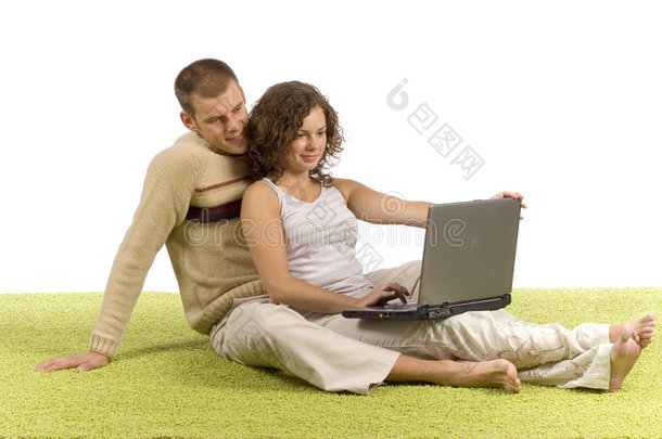 一对年轻夫妇带着笔记本电脑在<strong>绿地毯</strong>上