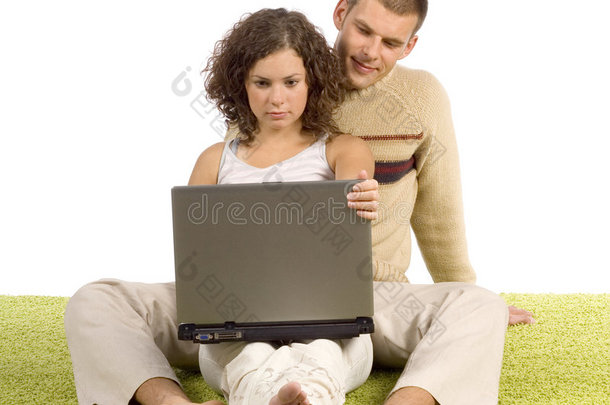一对年轻夫妇带着笔记本电脑在<strong>绿地毯</strong>上
