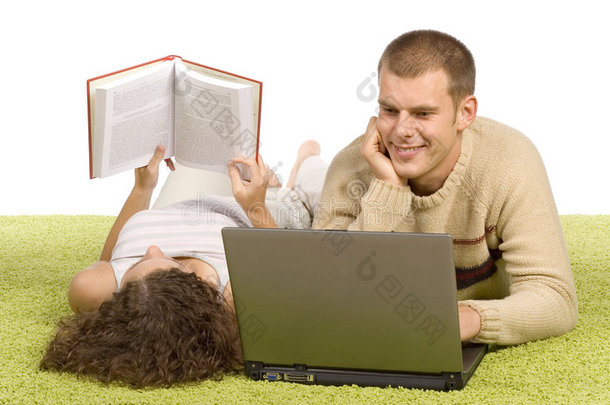 一对年轻夫妇带着笔记本电脑和书在<strong>绿地毯</strong>上