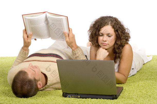 一对年轻夫妇带着笔记本电脑和书在绿地毯上