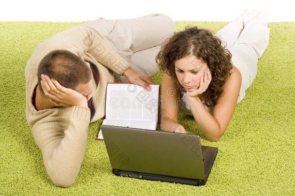 一对年轻夫妇带着笔记本电脑和书在<strong>绿地毯</strong>上