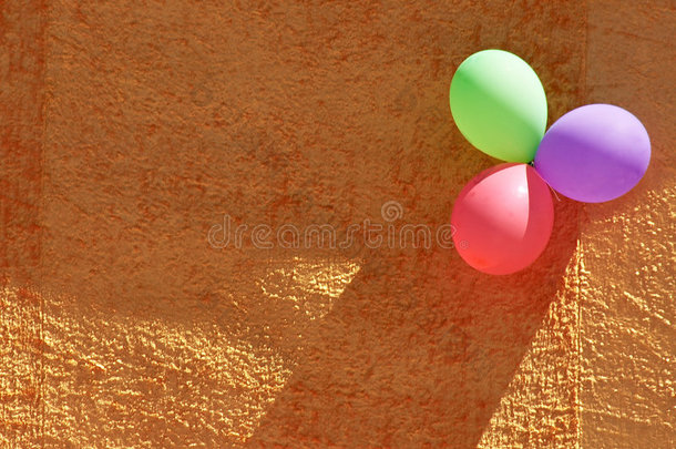 三个五颜六色的派对<strong>气球</strong>和橙色纹理的墙壁