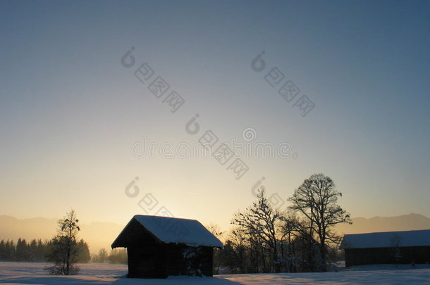 落日雪景中的孤寂小屋