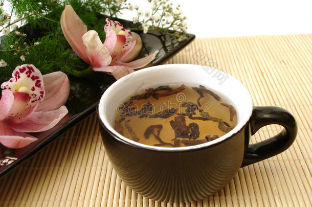一杯红叶兰花茶，放在黑色盘子里，用麦秸磨光