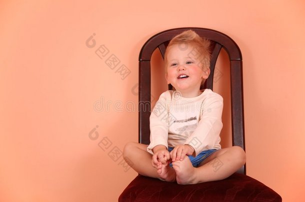 孩子坐在粉红色房间的椅子上
