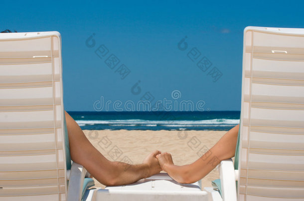 一对手牵着手坐在沙滩椅上的夫妇