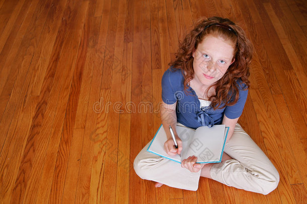 坐在地板上写字的小女孩