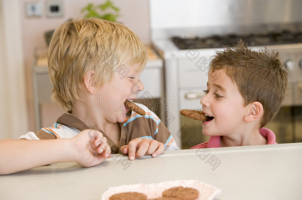 两个小男孩在厨房里笑着吃饼干