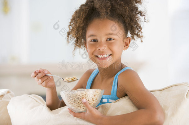 在客厅吃麦片的小女孩微笑着