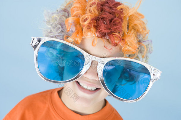 戴着小丑假发和太阳眼镜的小男孩微笑着