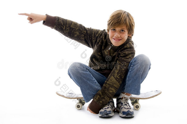 坐在滑板上指指点点的男孩