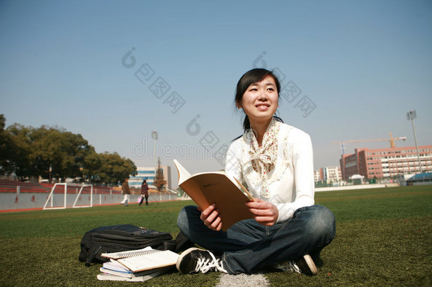 坐在草地上拿书的女孩