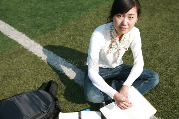坐在草地上拿书的女孩