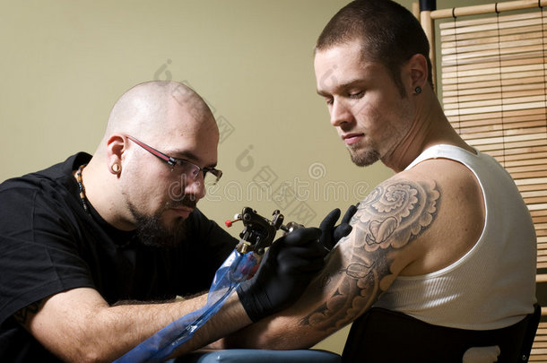 纹身师专注于给某人纹身