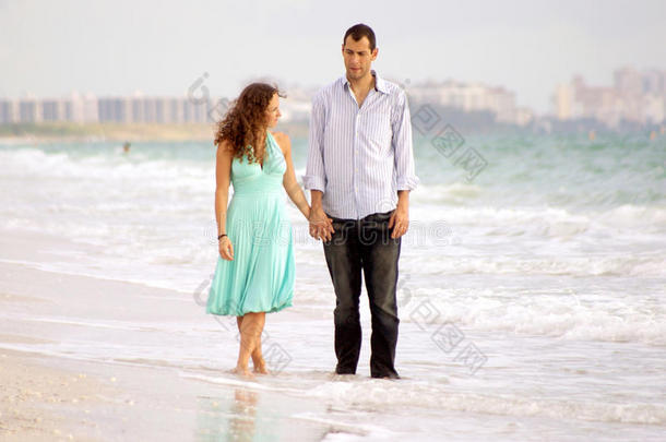 走在沙滩上讨论问题的年轻夫妇