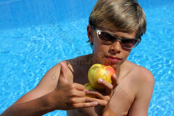 戴太阳眼镜的男孩展示一个苹果