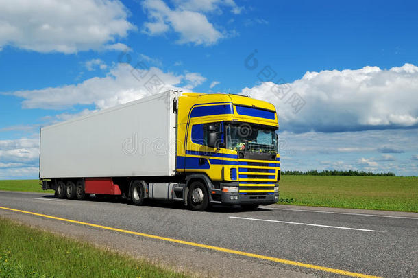 蓝黄色车厢的卡车在高速公路上行驶。