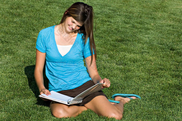 在草地上学习的漂亮少女