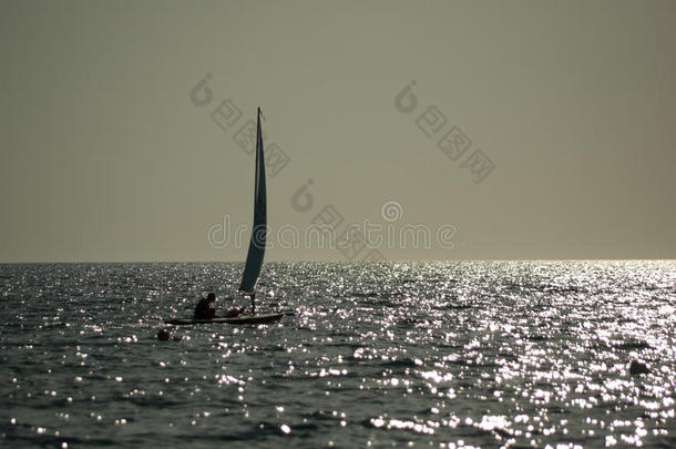 日落时在平静海面上航行的小帆船