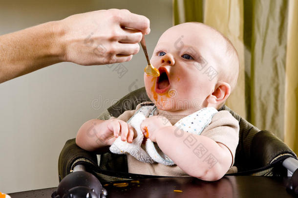 饥饿的婴儿用勺子吃固体食物