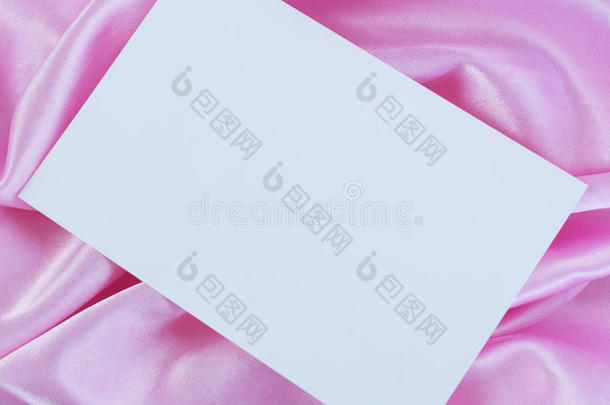 粉色缎子上的空白白色卡片