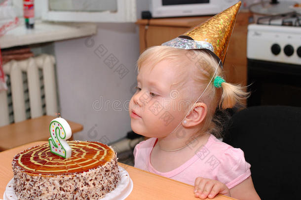 戴着<strong>生日帽</strong>和生日蛋糕的漂亮小女孩。