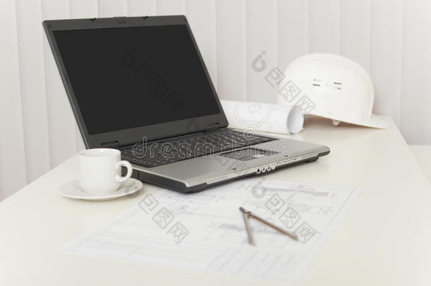 桌上的笔记本电脑、图纸、头盔和圆规