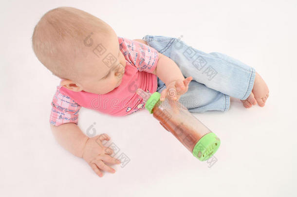 小孩拿着一个放在地板上的瓶子