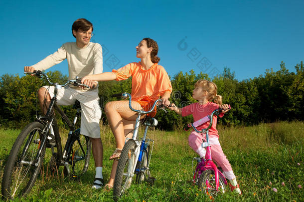 <strong>爸爸妈妈</strong>和女儿在公园里骑自行车