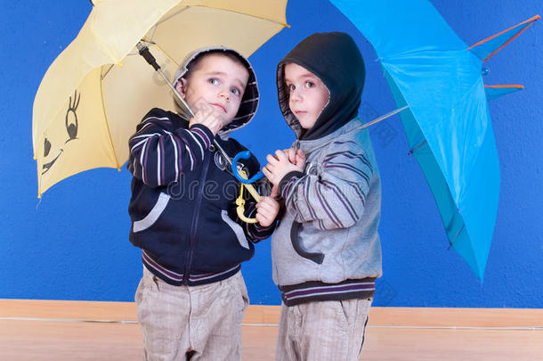 双胞胎兄弟在雨伞下玩得很开心