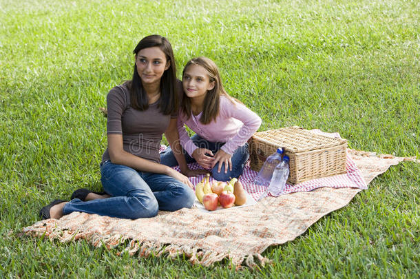公园里坐在草地上野餐毯上的女孩们