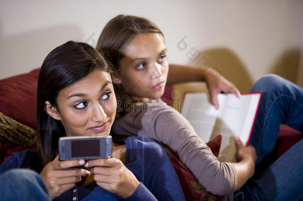 两个躺在沙发上的女孩在发短信时<strong>抬头</strong>看了看