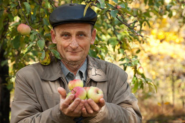 有苹果的中年男子站在苹果树旁