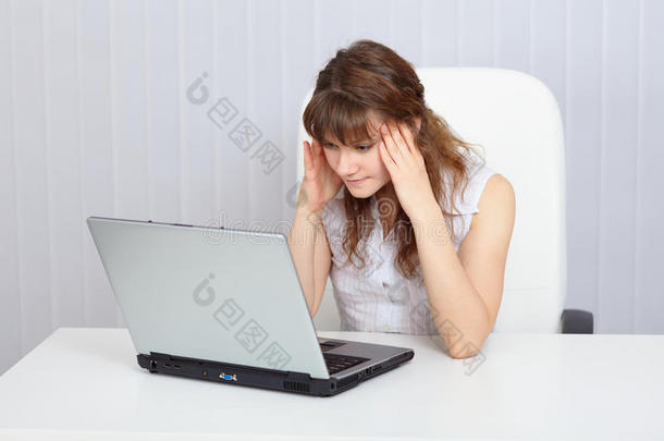 年轻疲倦的妇女在桌上用笔记本电脑工作