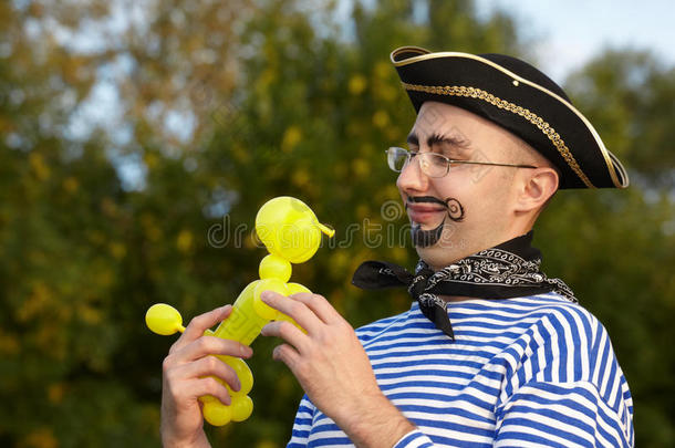 一个穿着海盗服的男人看着小狗的<strong>气球</strong>。