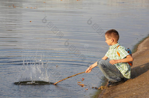 池塘边背着背包的小男孩