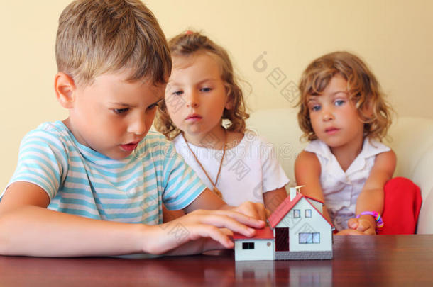 三个孩子一起看房子模型
